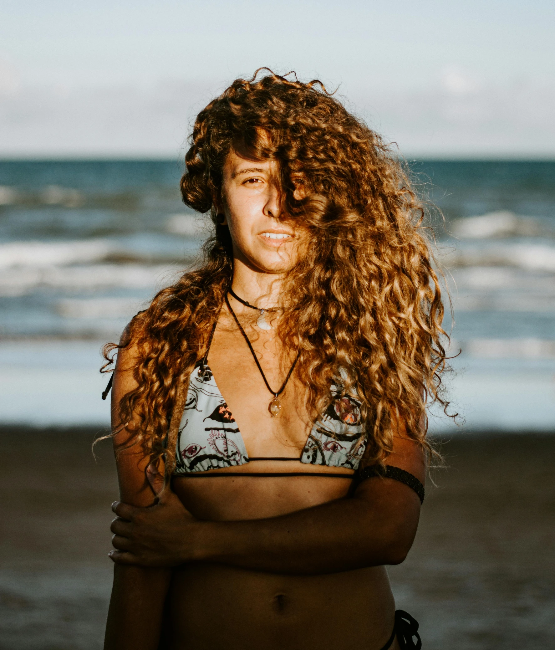 a woman with long curly hair standing next to the water