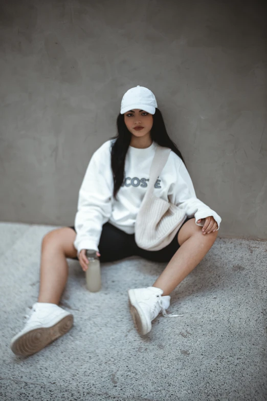 a girl sitting on the ground in white sweater and ripped jeans