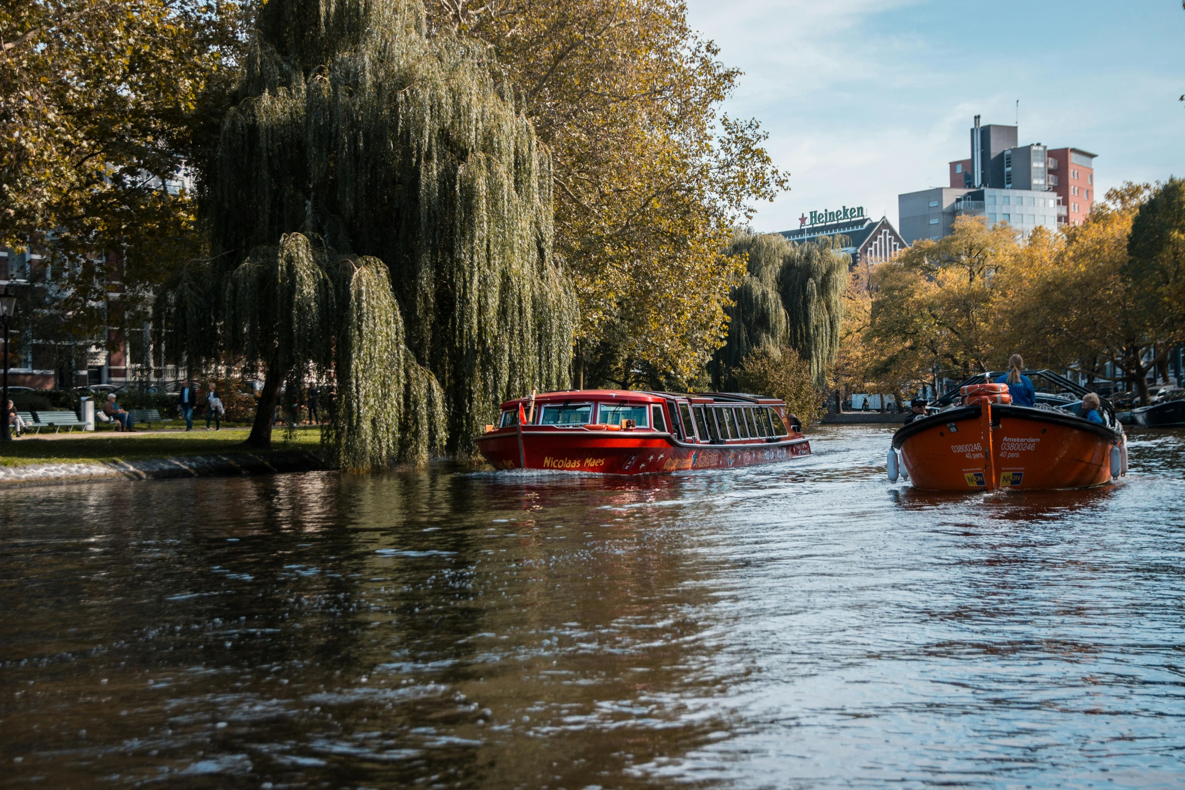 red boats are passing by a row of trees