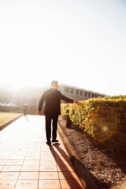 a person walking on a pathway holding hands with the sun shining in the background