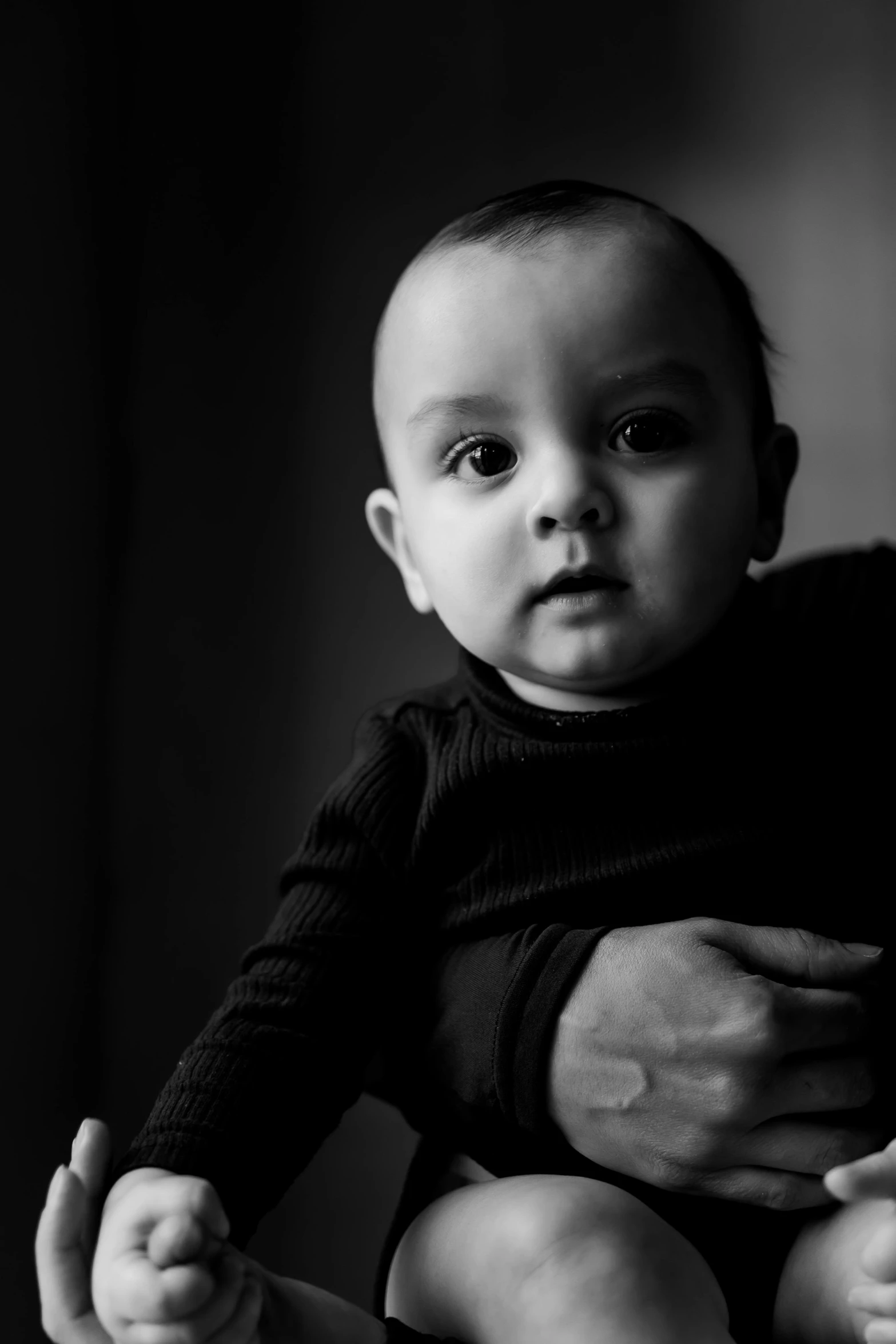 a baby sitting on someone's lap in black and white