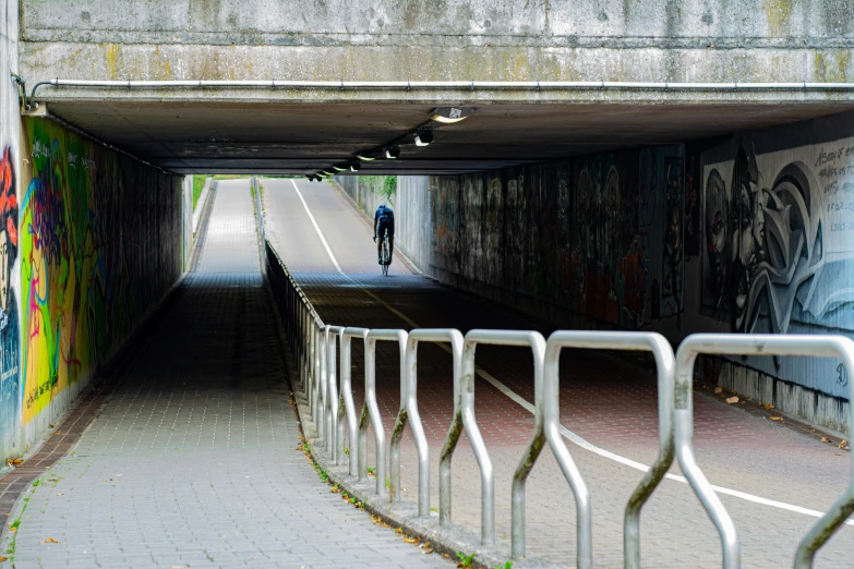 two people riding bikes in an underpass with graffiti