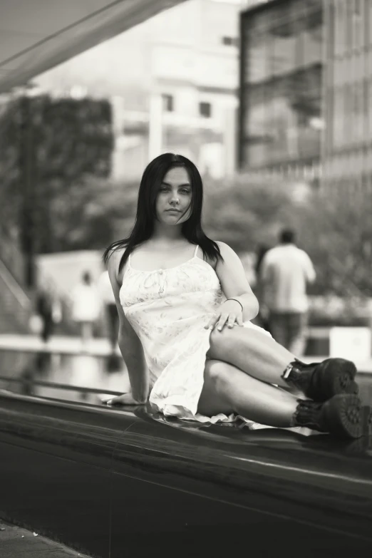 a girl in white dress sitting on wall in city