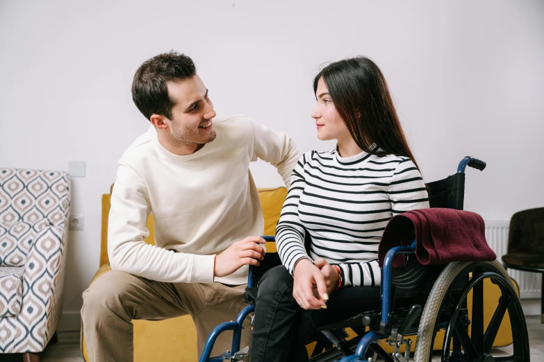 a man sitting next to a woman in a wheelchair