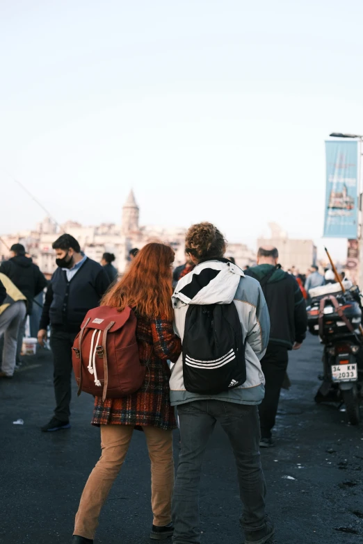 a couple holding each other while walking past a crowd of people