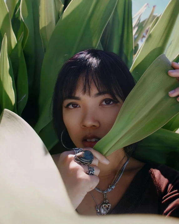 a woman holding on to the green leaves of a plant