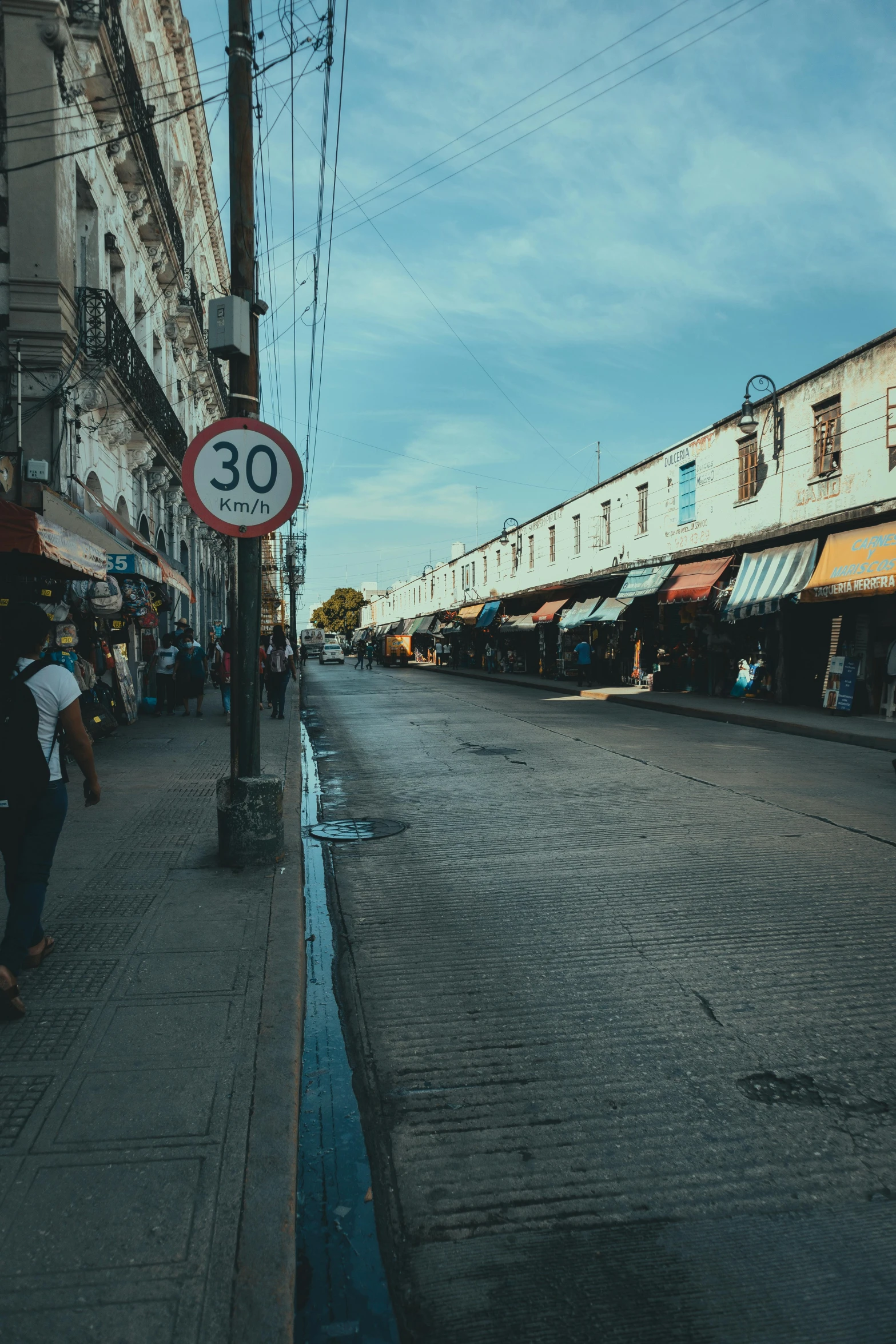 people walking on a city sidewalk next to a sign