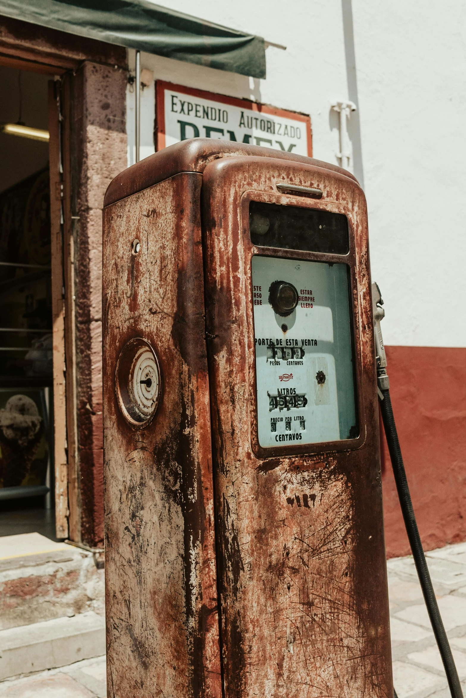 an old rusty gas pump on the side of a road