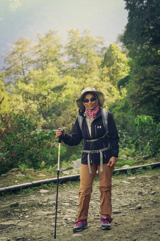 a lady wearing sunglasses and a hat holding a trek pole