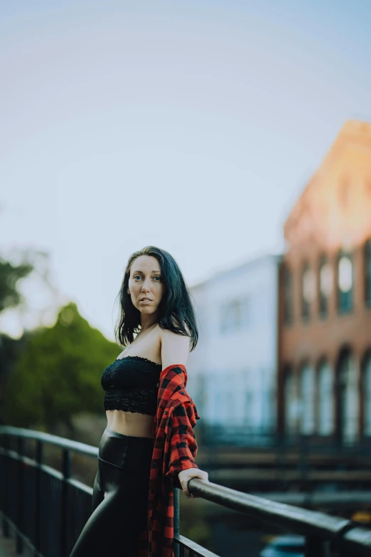 a woman is standing on the bridge wearing a plaid shirt and black pants