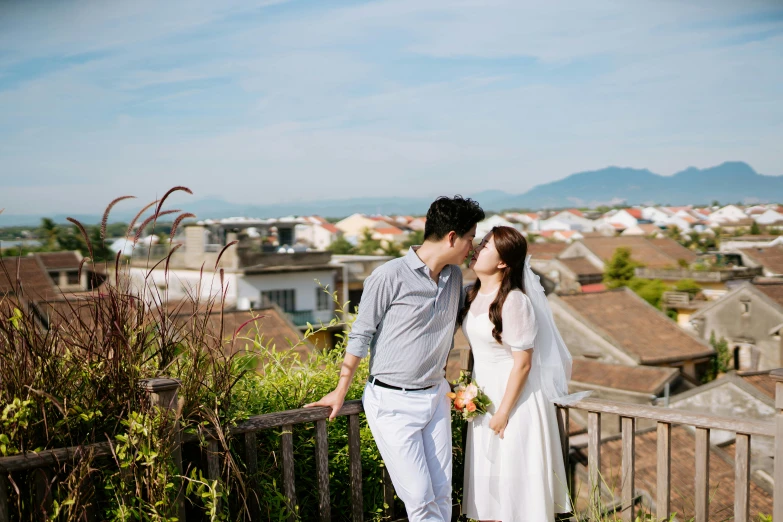 a couple posing for their wedding picture on top of the hill