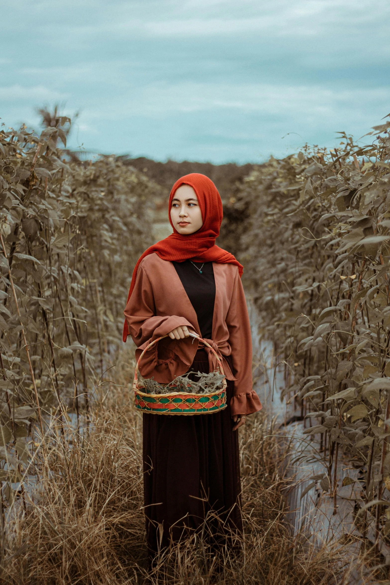 woman in brown and red wearing dress walking through long grass