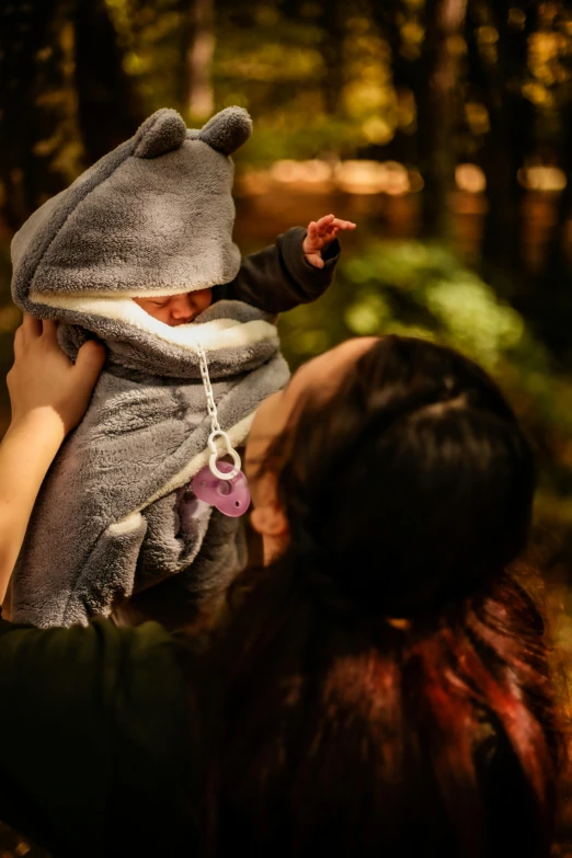 a woman holding a baby while wearing a bear blanket