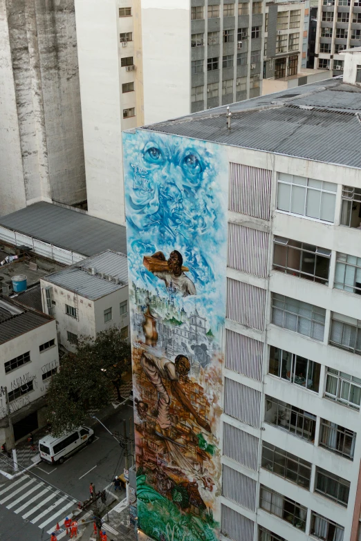 a very tall mural by some buildings on the side of a building