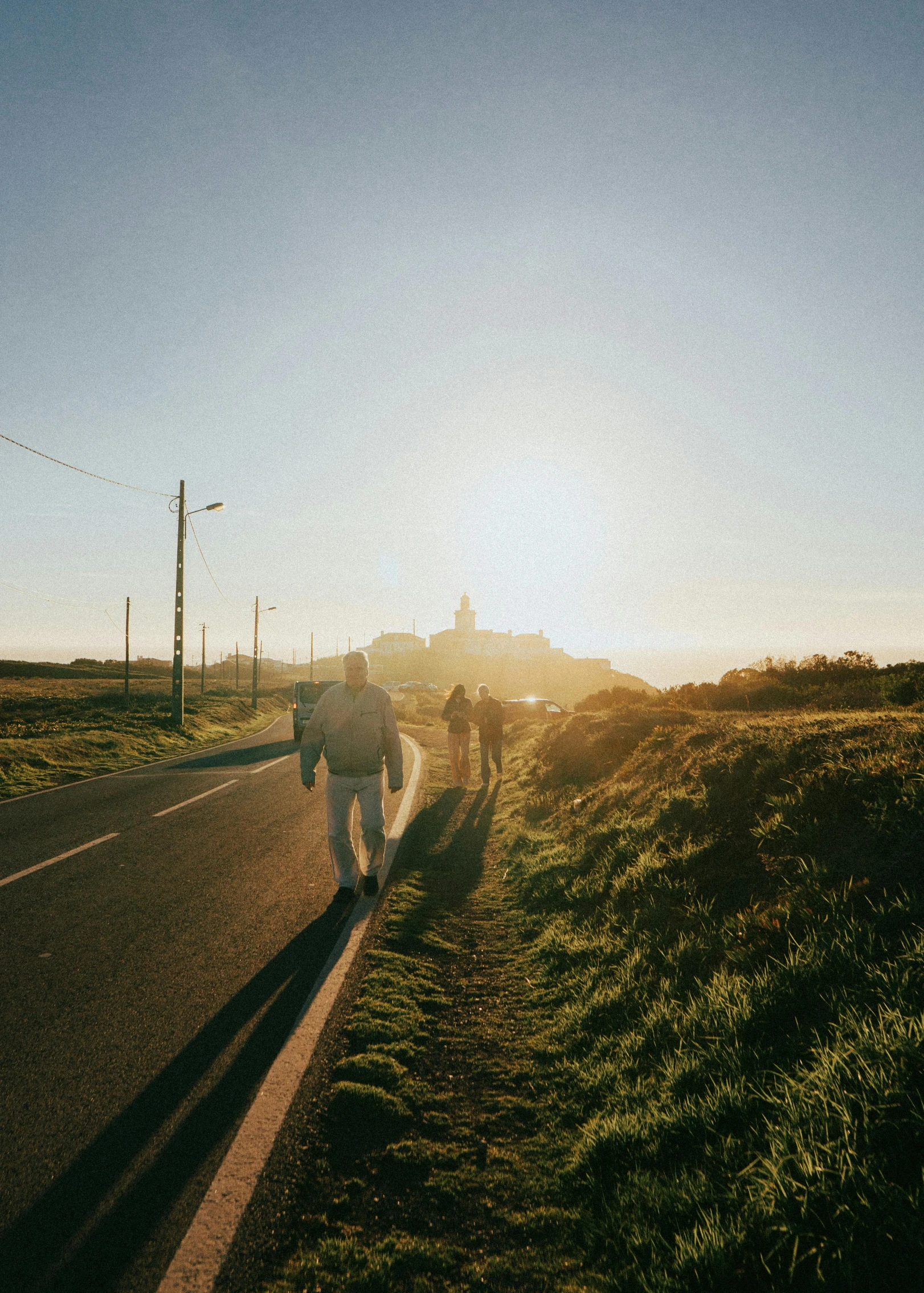 several people are walking along a grassy road