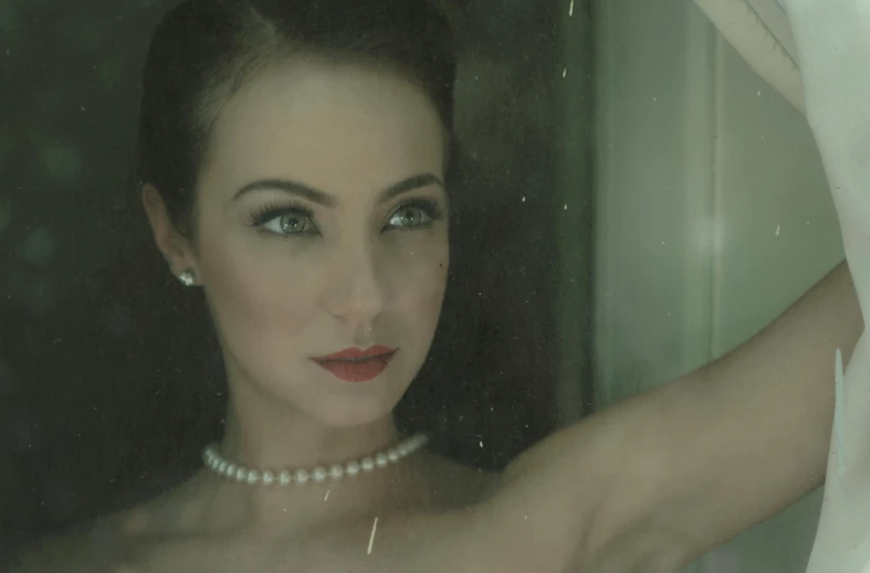 a woman looking into a mirror while wearing pearls