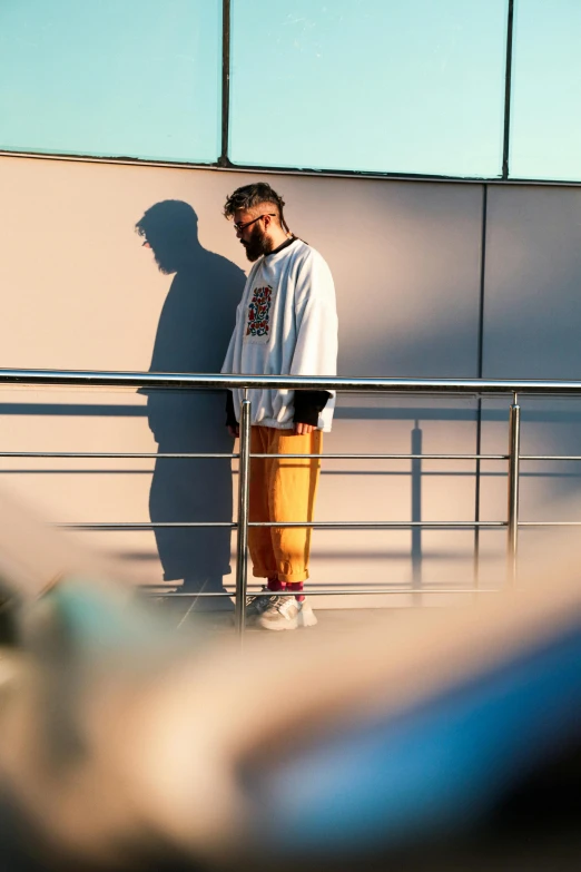 man in jacket standing by railing against wall