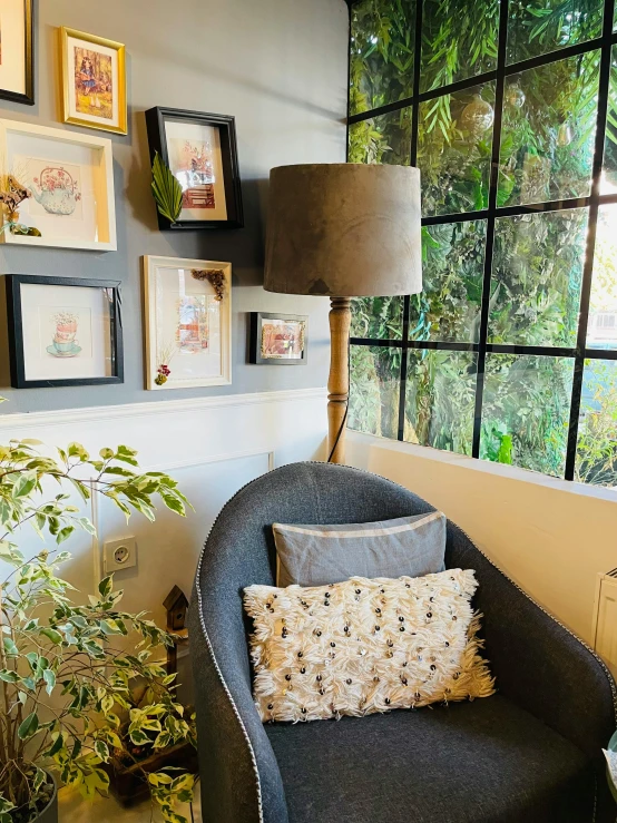 an upholstered chair in a corner of a room with several framed pos on the wall