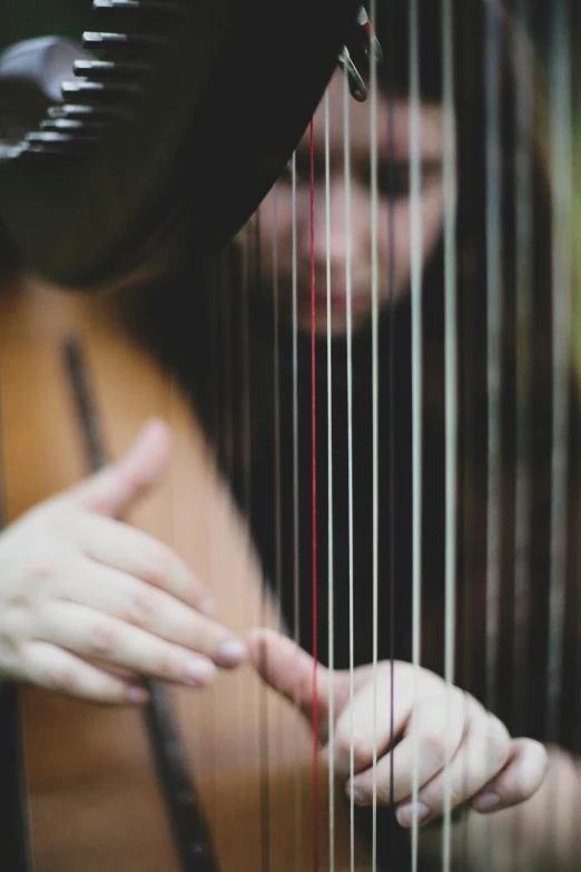 the hand of a woman holding a strings harp