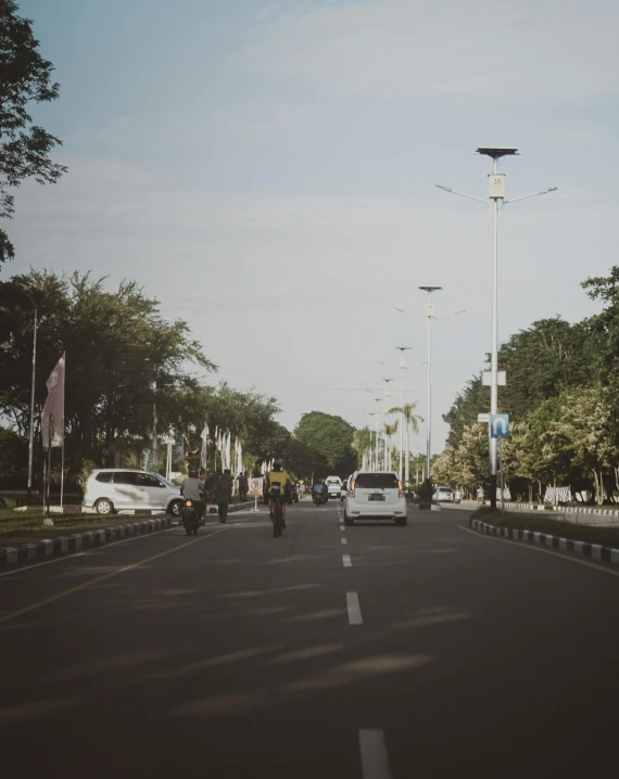 a city street with cars and motorcycle on both sides