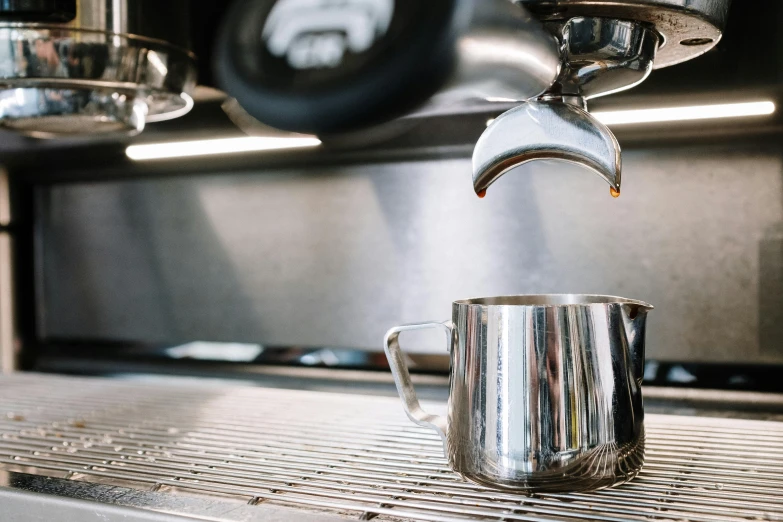 a silver cup is being stirred with a tea kettle