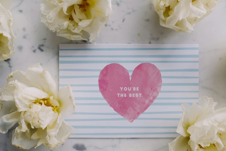 a heart on a blue striped card with white flowers around it