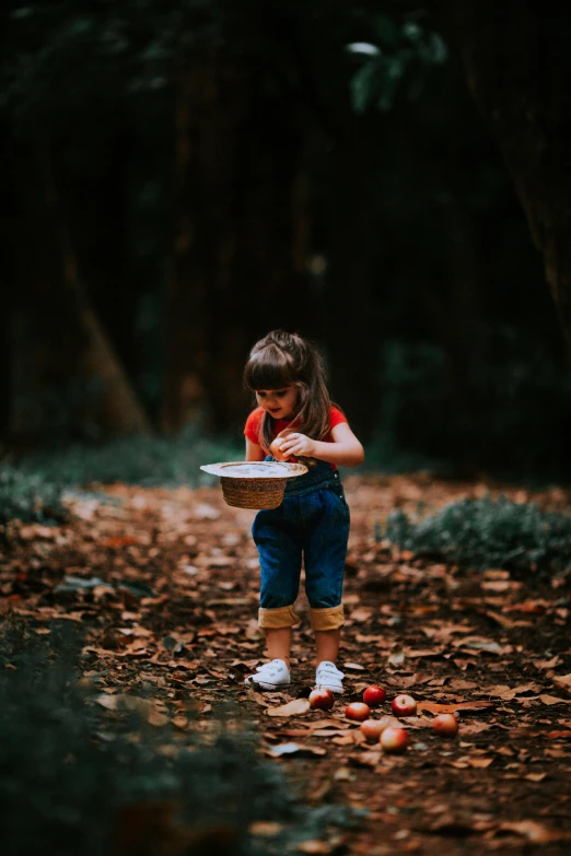 a little girl holding a plate and looking at soing on the ground