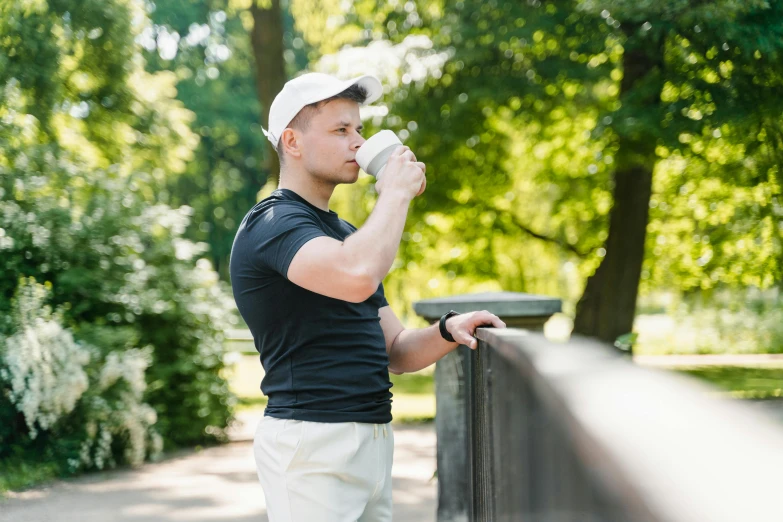 man in black shirt and white cap drinking out of mug