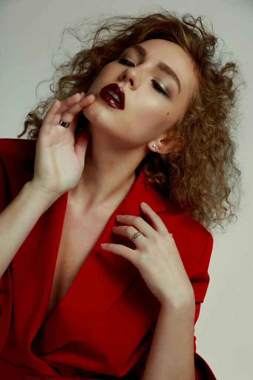 a woman in red dress holding up her hand and looking up at the camera