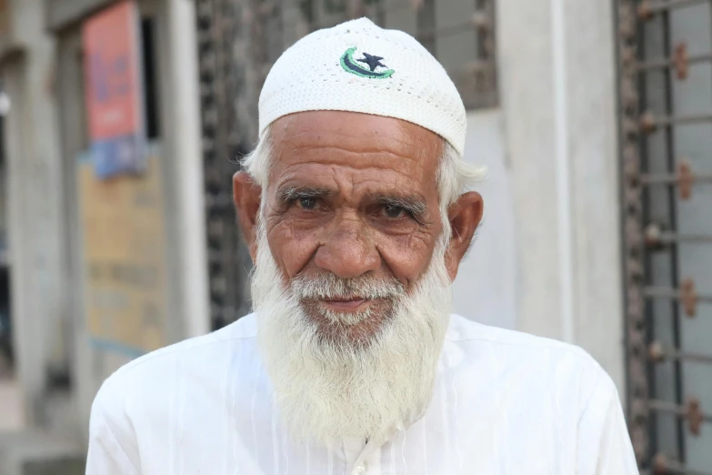 an old man in white standing outside on the street