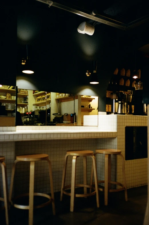 the inside of a restaurant, with a counter and stools in front of it