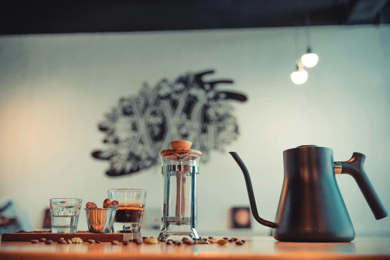 a carafe and glasses sit on a counter, as well as two tea kettles