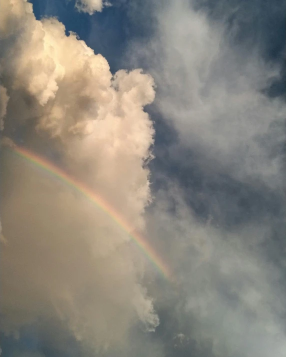 an rainbow appears in a cloudy blue sky