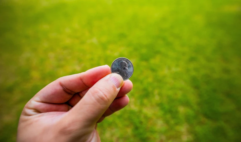 a persons hand is holding a tiny disc outside