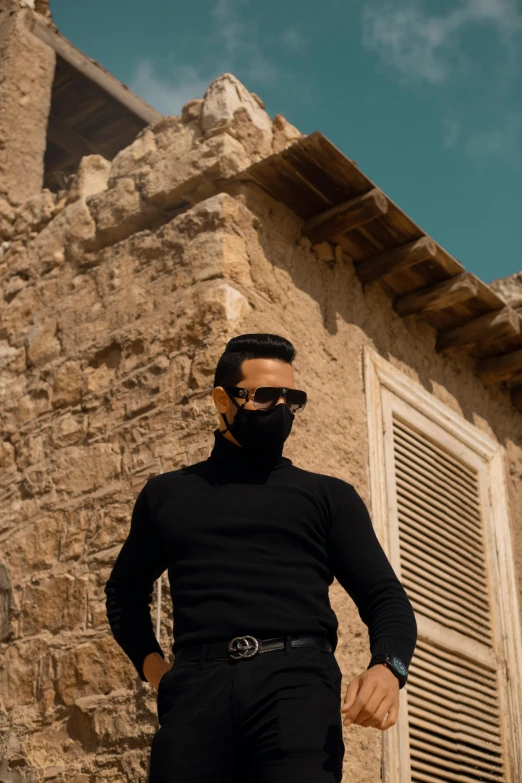 a man in a black shirt wearing sunglasses and a scarf on his face