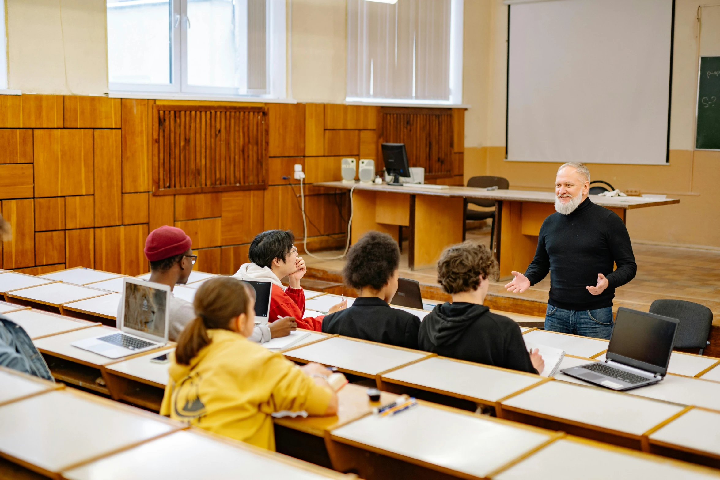 many students sitting at desks looking towards an instructor