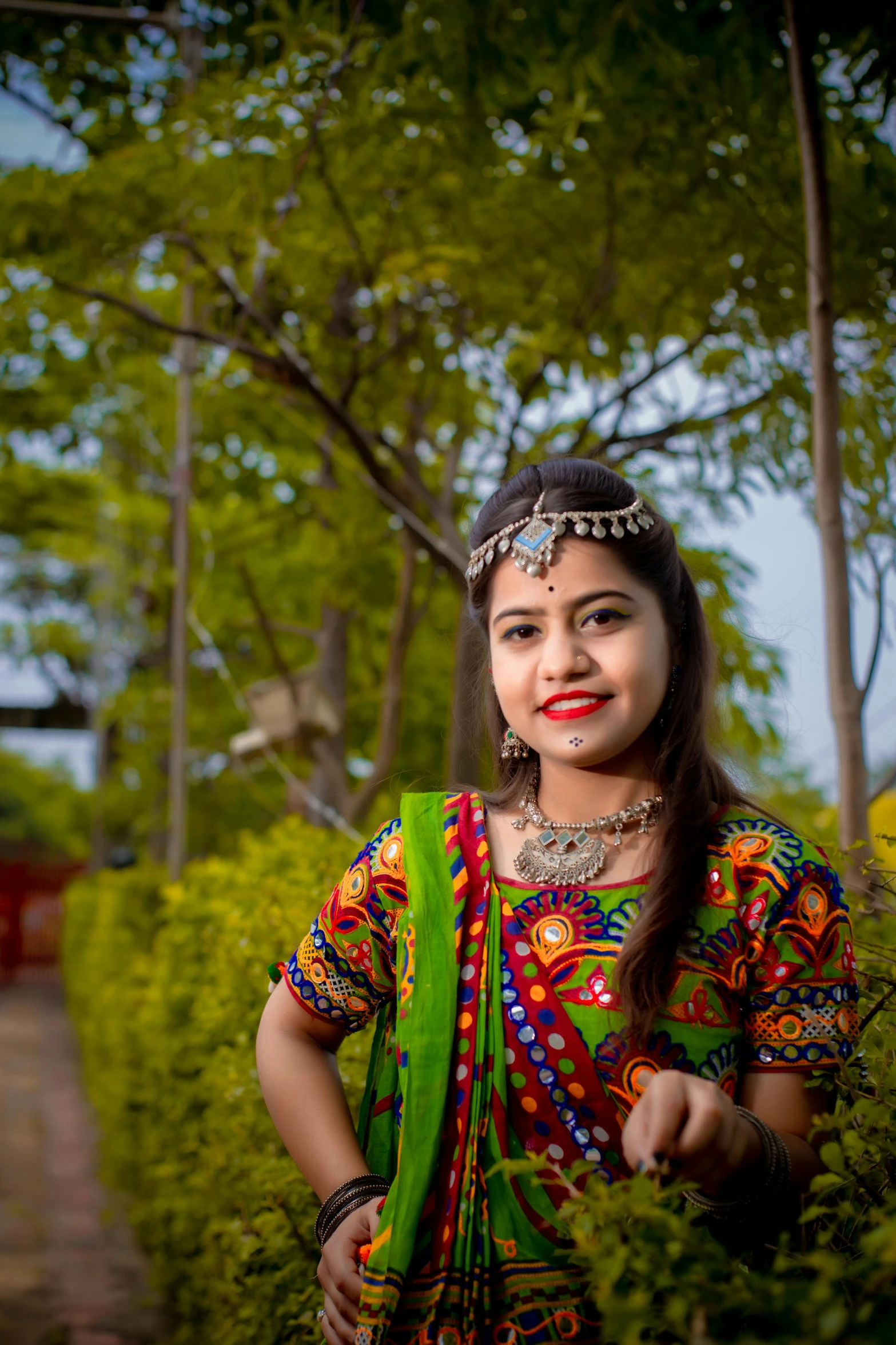 woman with green and red cloth standing in tree - lined area