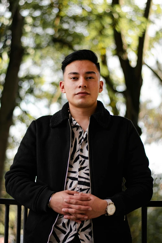 a man with his arms folded and standing near trees