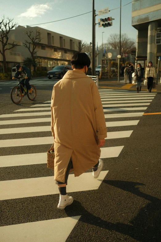 the man in an trench coat is crossing a crosswalk