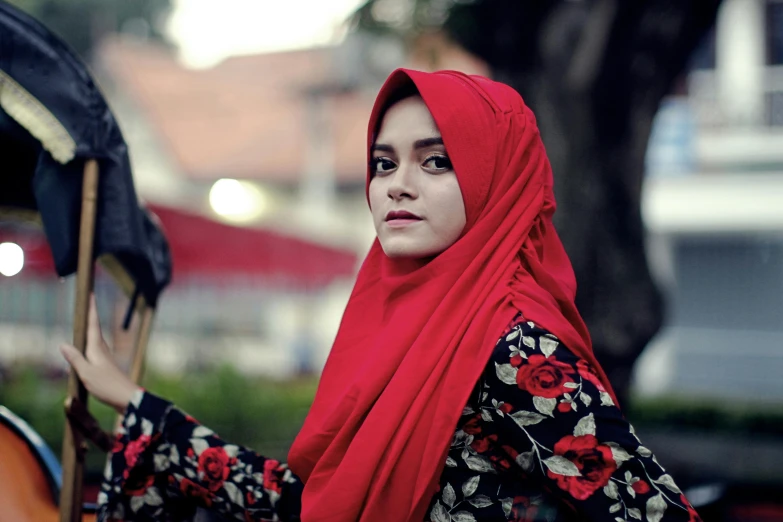 woman dressed in hijab holding musical instrument with city lights in background