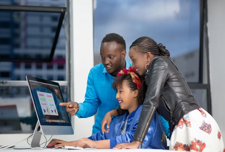 there are people at a computer that has a man and woman looking at it