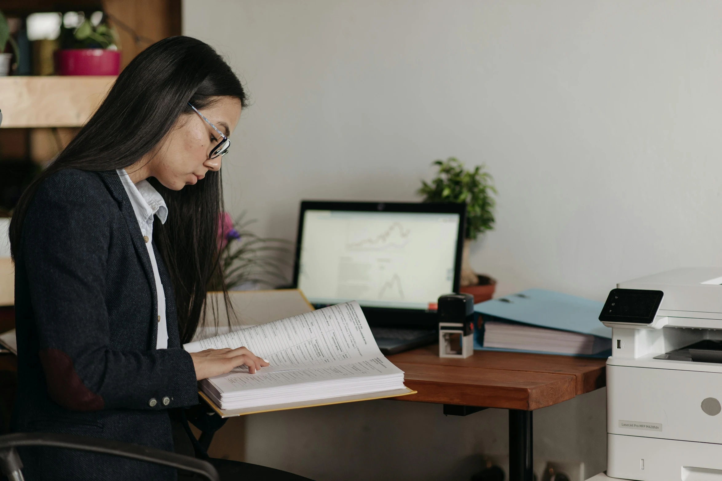 a woman wearing glasses is looking at a book in an office