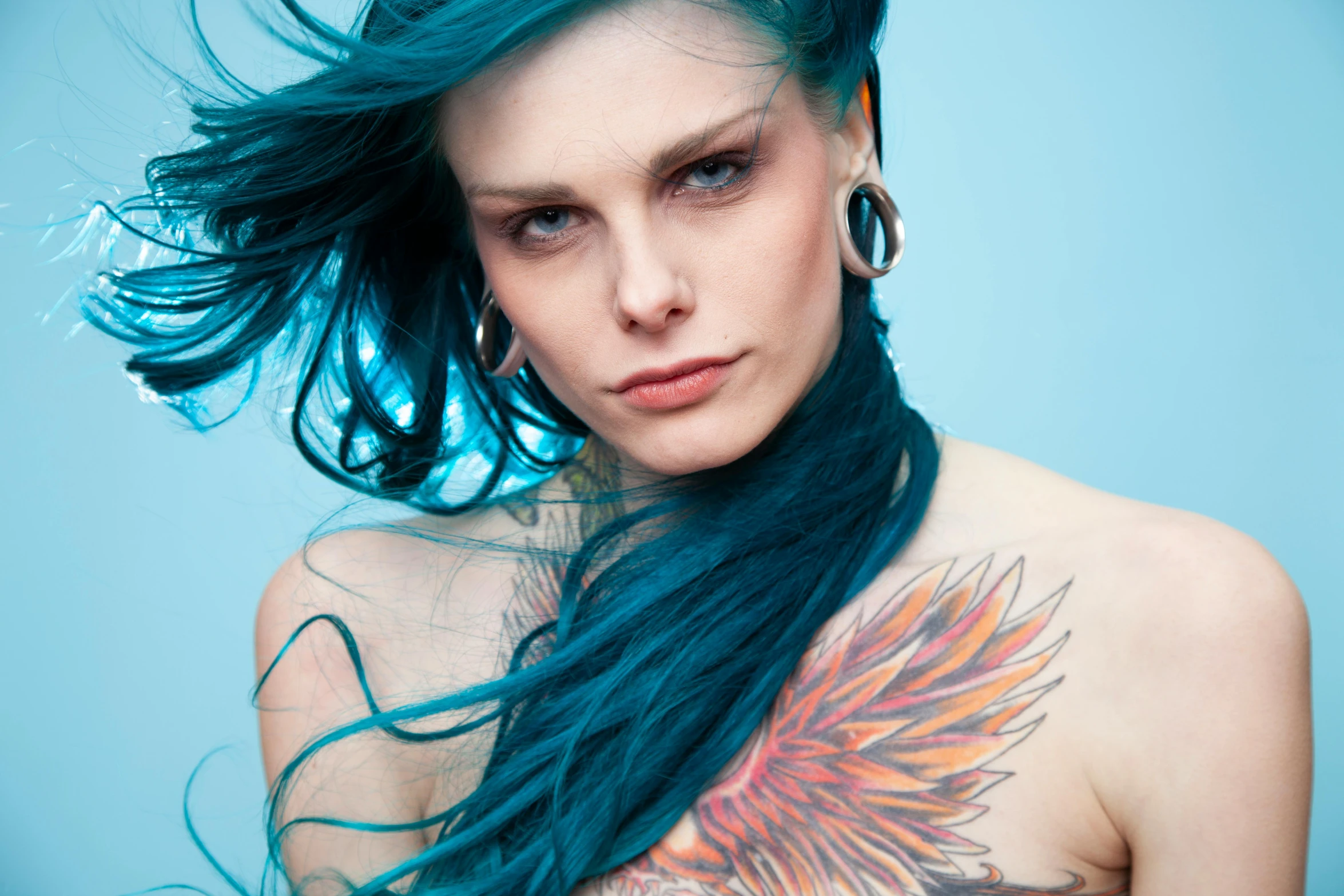 a woman with blue hair and colorful tattoo on her back