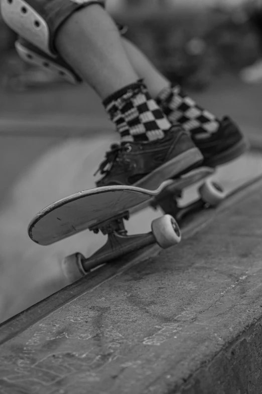 the legs of a man riding a skateboard on top of cement