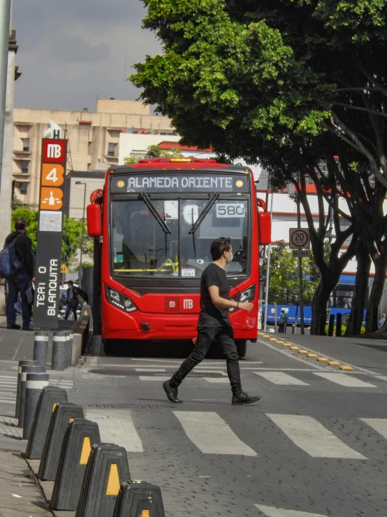 a man walking across the street near a bus