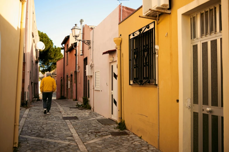 a man walks down a narrow street in the old part of town