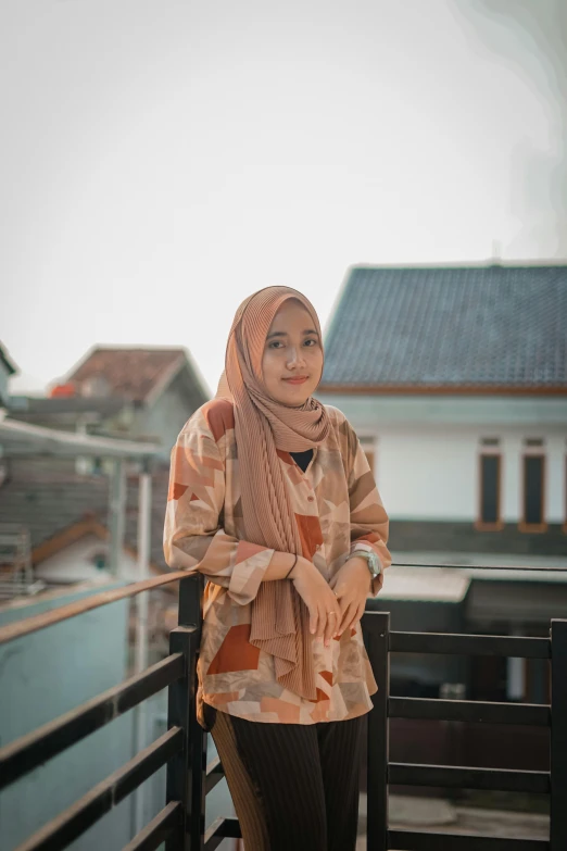 a woman is standing on a bridge with a scarf around her head