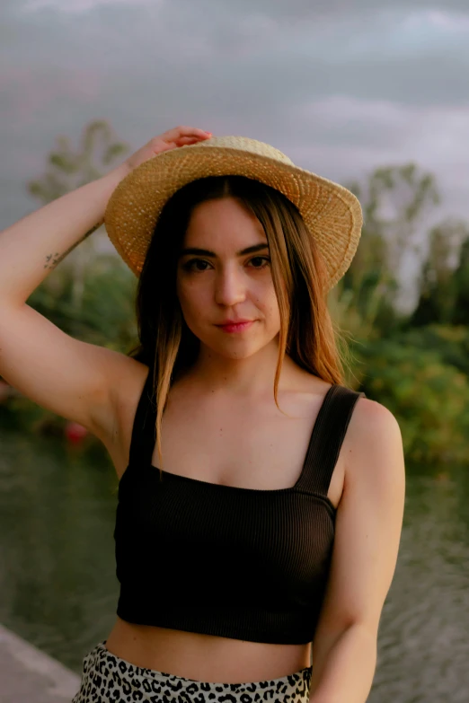 a young woman poses with a hat on her head