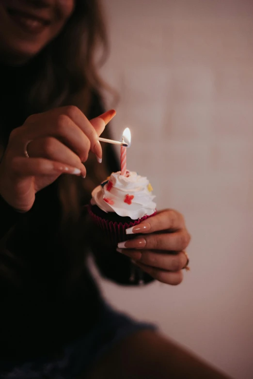 someone holding a birthday cupcake with a single candle
