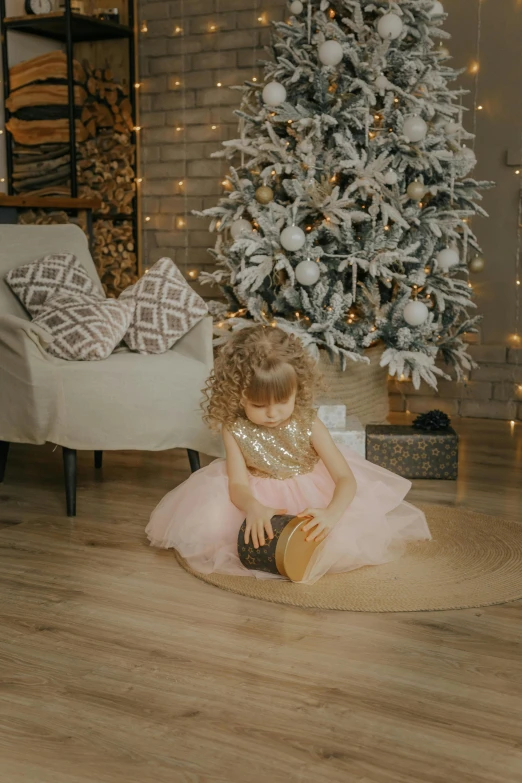 a little girl dressed in a pink dress sitting on a circle rug